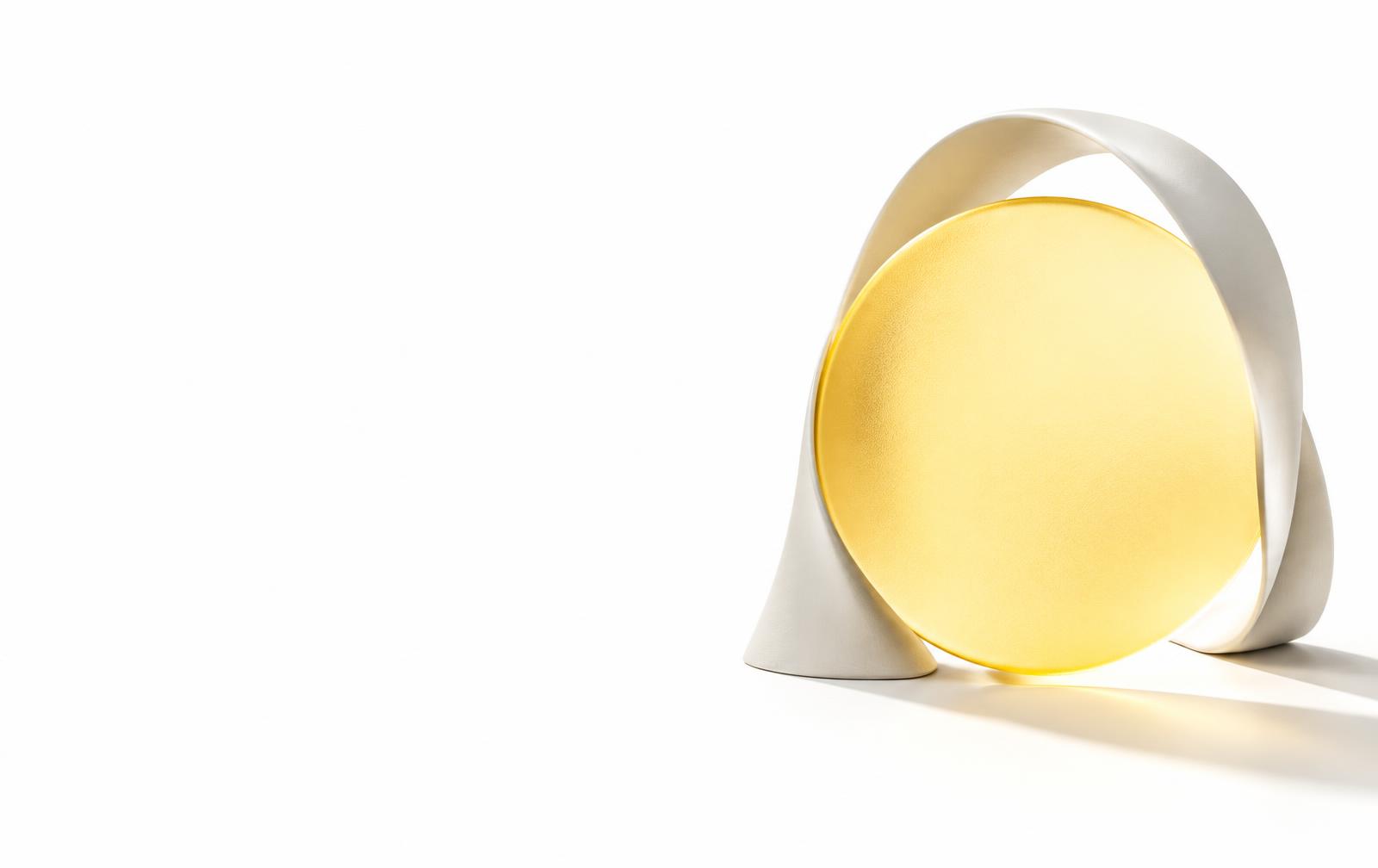 Eine leuchtend gelbe Glasscheibe, von einer weißen Skulptur ins Licht gerückt